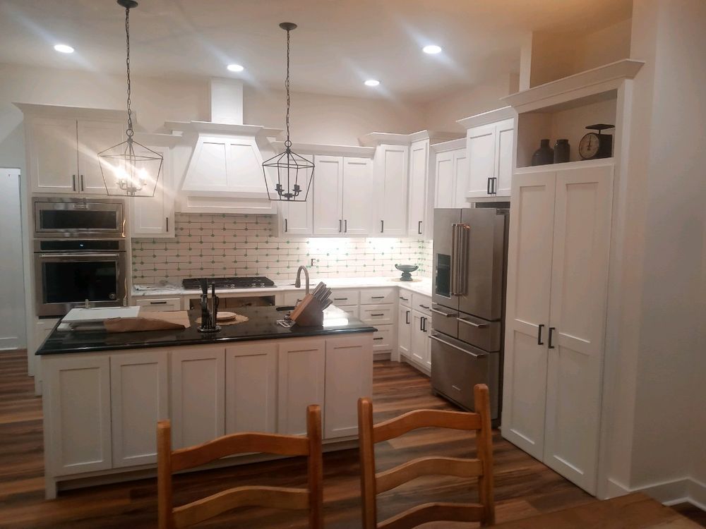 White kitchen with island, stainless steel appliances, and dark countertops.