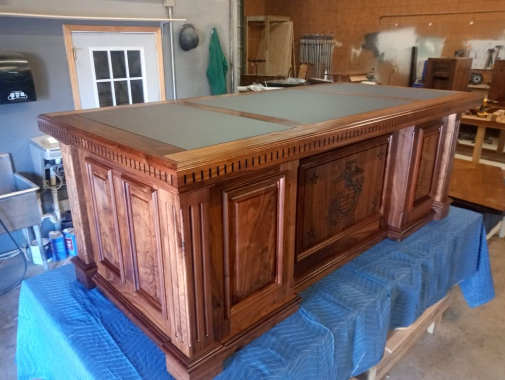 Wooden executive desk with leather top, in a workshop setting.