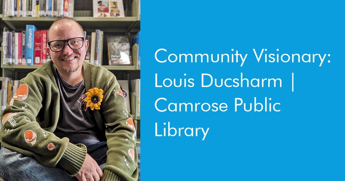Louis Ducsharm, a programmer at the Camrose Public Library, sits among the library book shelves.