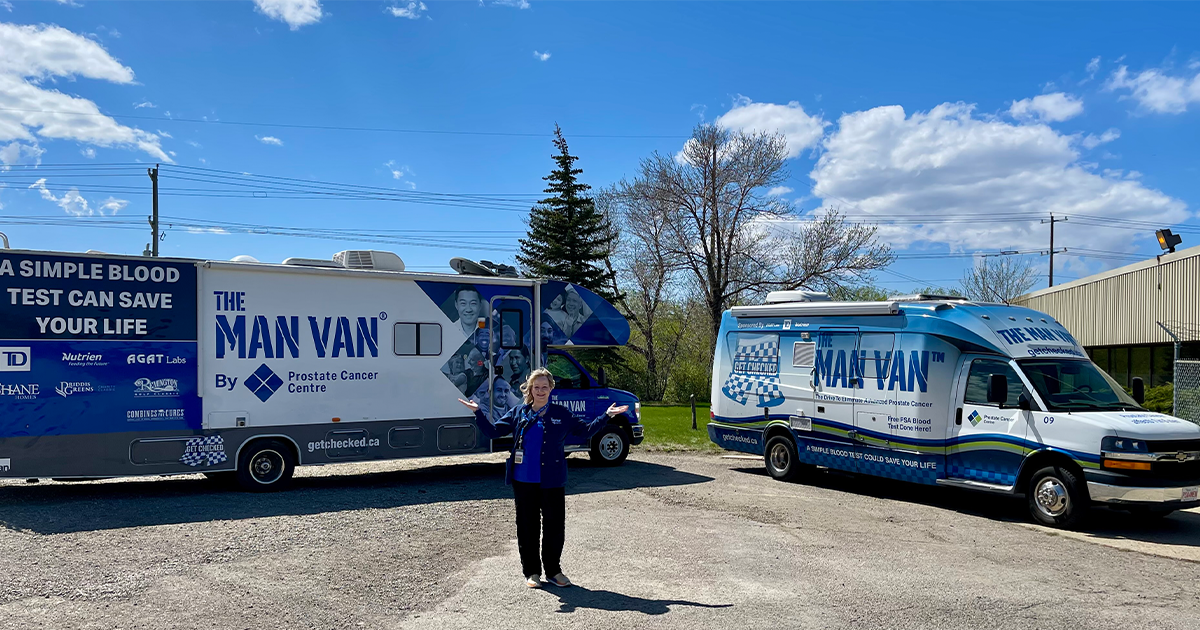 Camille Scheible, Director of The MAN VAN®, stands in front of two MAN VAN mobile clinics.