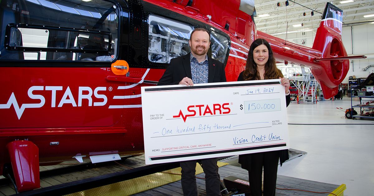 Dan Hautzinger of Vision Credit Union and Alison Hagan of STARS stand by helicopter with donation.