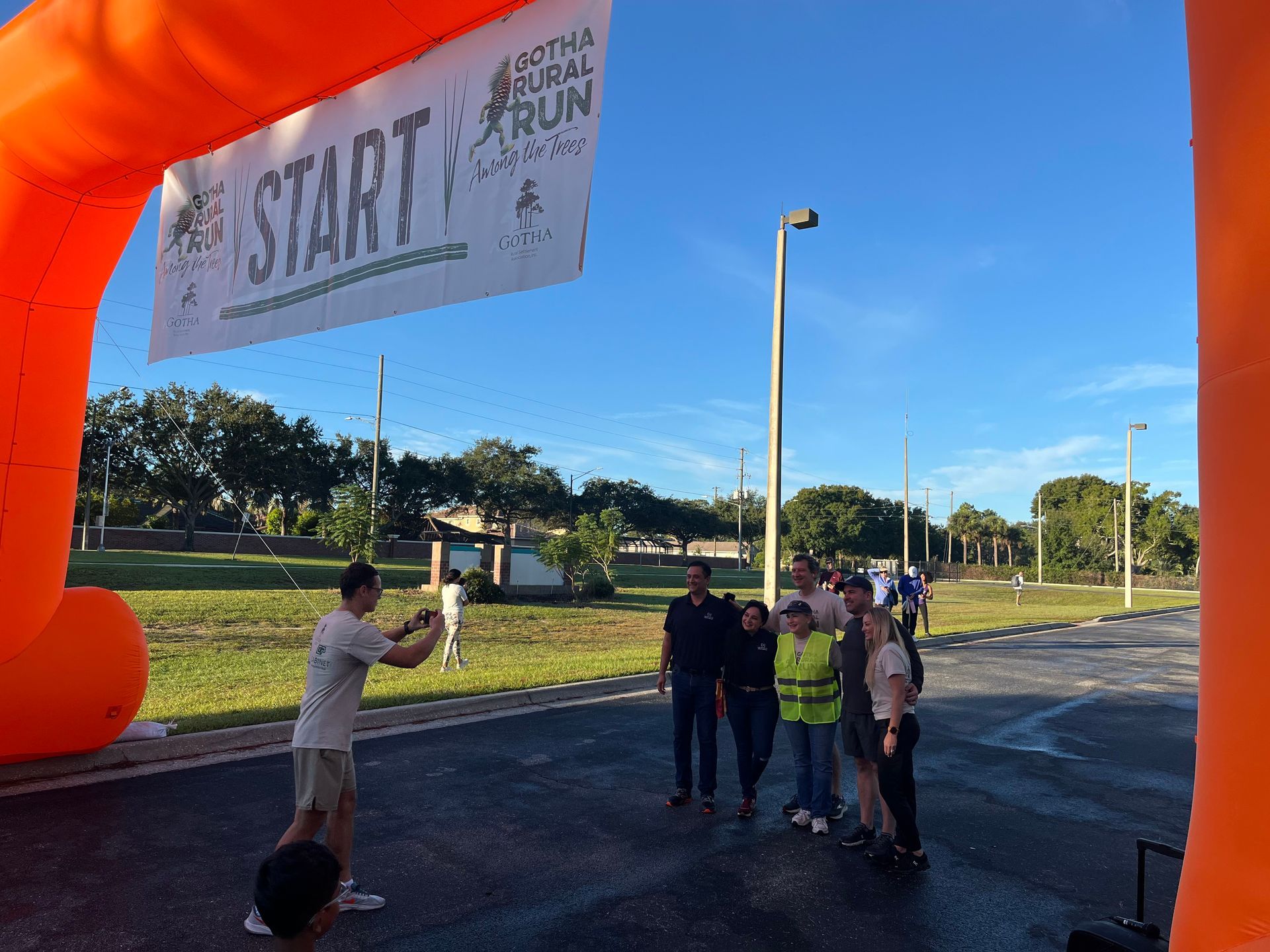 Group poses under bright orange start banner at Gotha Rural Run event.