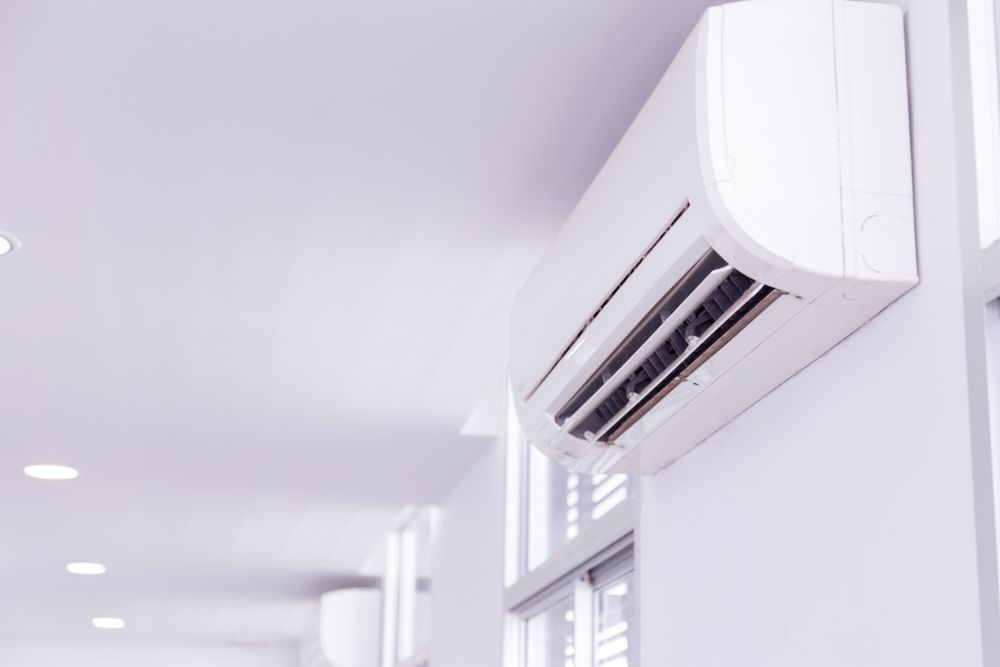 A White Air Conditioner is Hanging on a White Wall in a Hallway —​ Centre Evap & Home Maintenance Services in Ciccone, NT