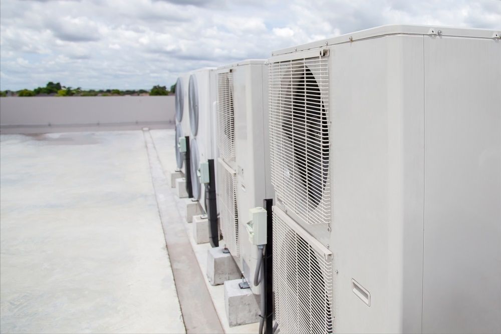 A Row of Air Conditioners Are Lined Up on the Side of a Building — Centre Evap & Home Maintenance Services in Ciccone, NT