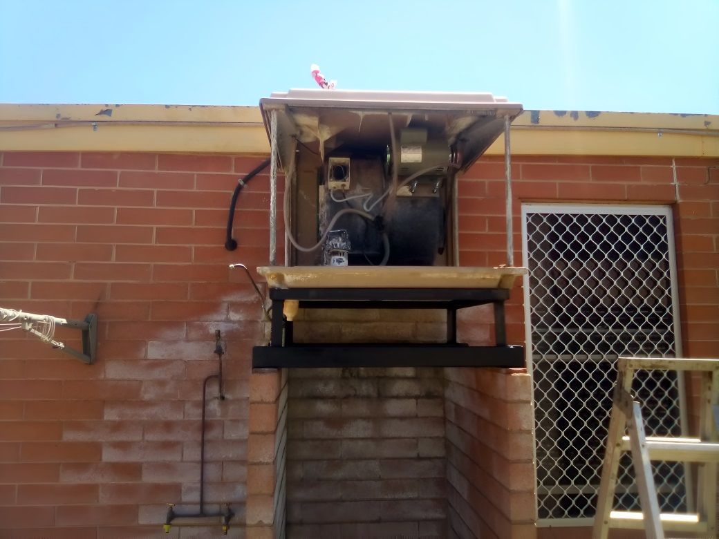 A Brick Building With a Ladder in Front of It —​ Centre Evap & Home Maintenance Services in Ciccone, NT