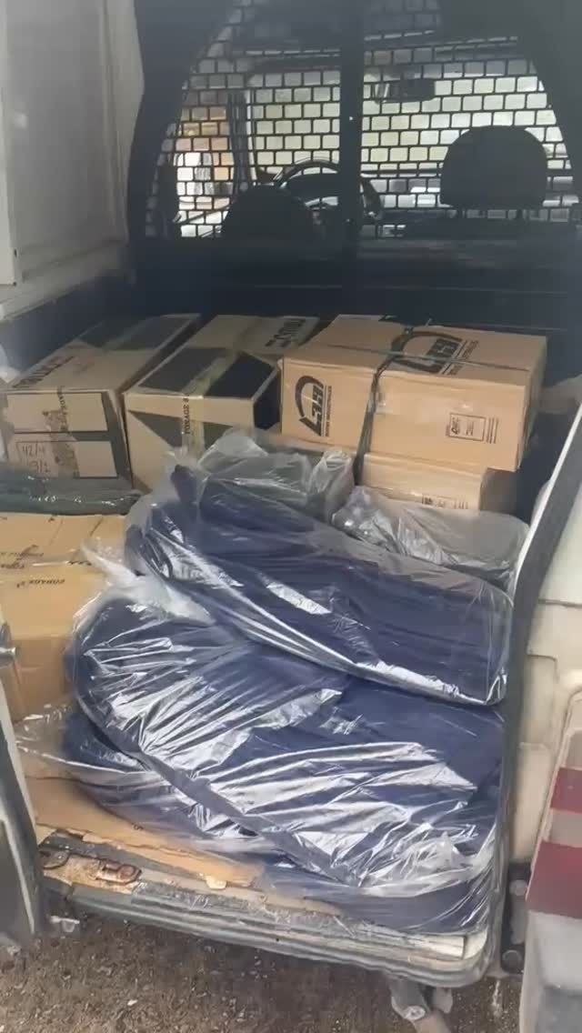 Cajas embaladas y artículos envueltos en plástico apilados en la parte trasera de la zona de carga de una furgoneta o camión.