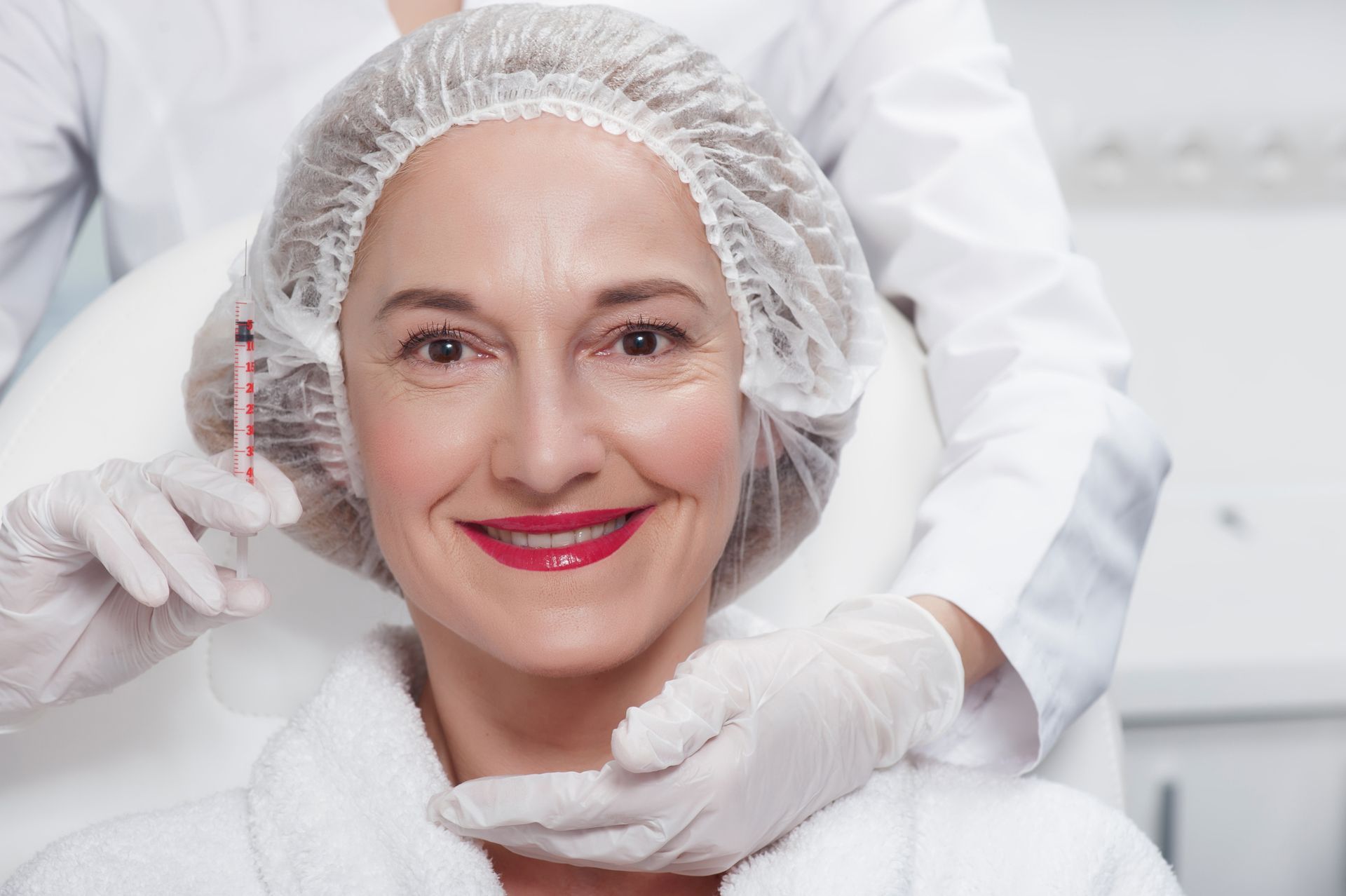 A woman is smiling while getting a botox injection in her face.