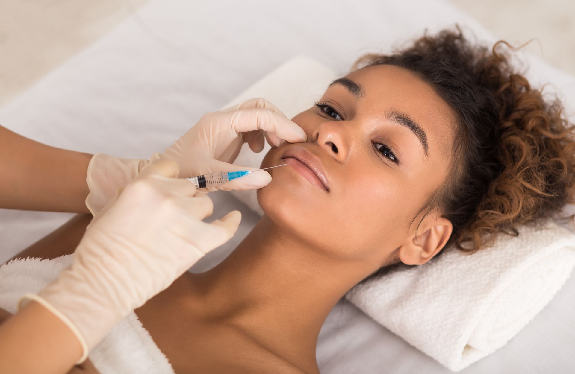 A woman is getting a botox injection in her lips.