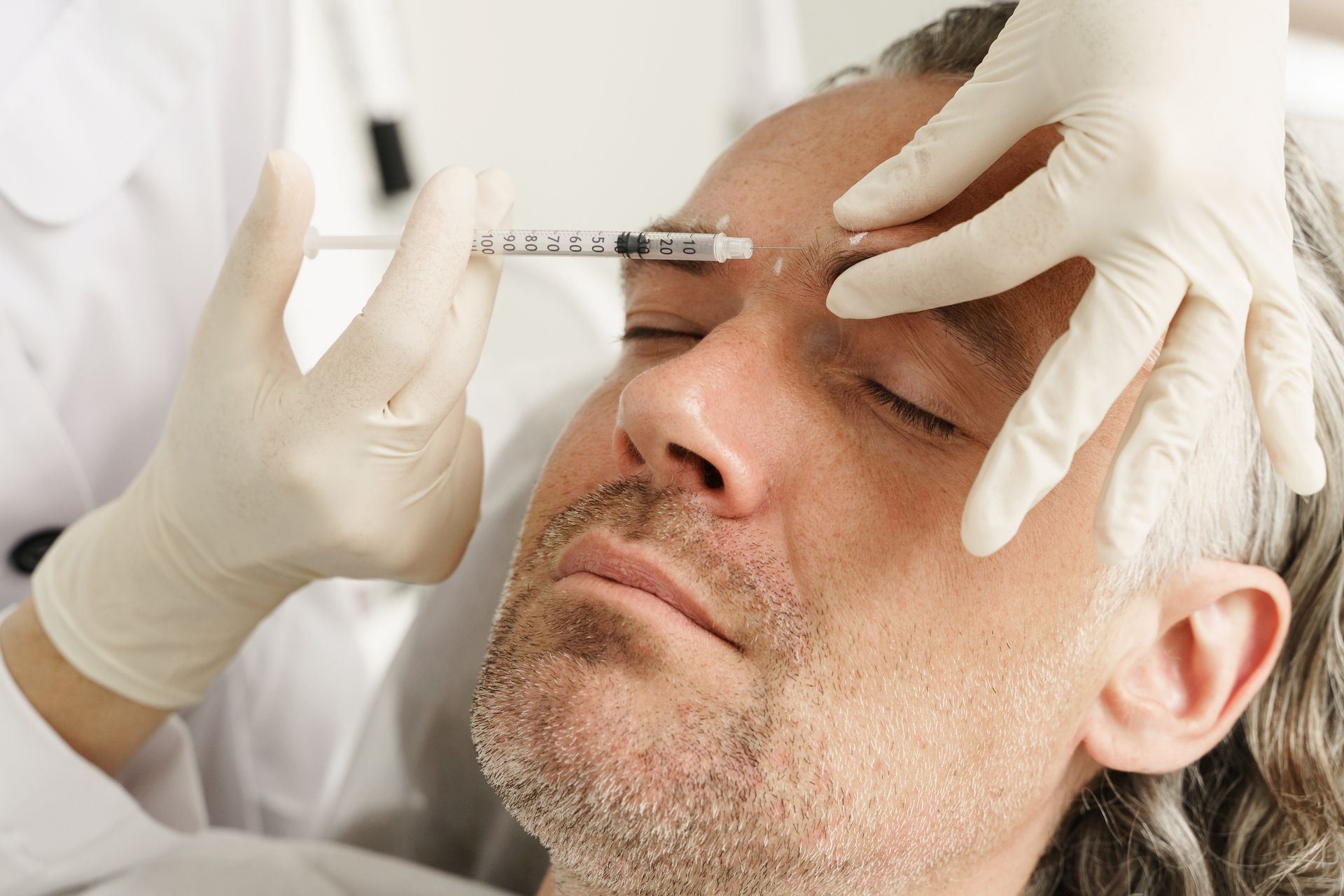 A man is getting a botox injection in his forehead.