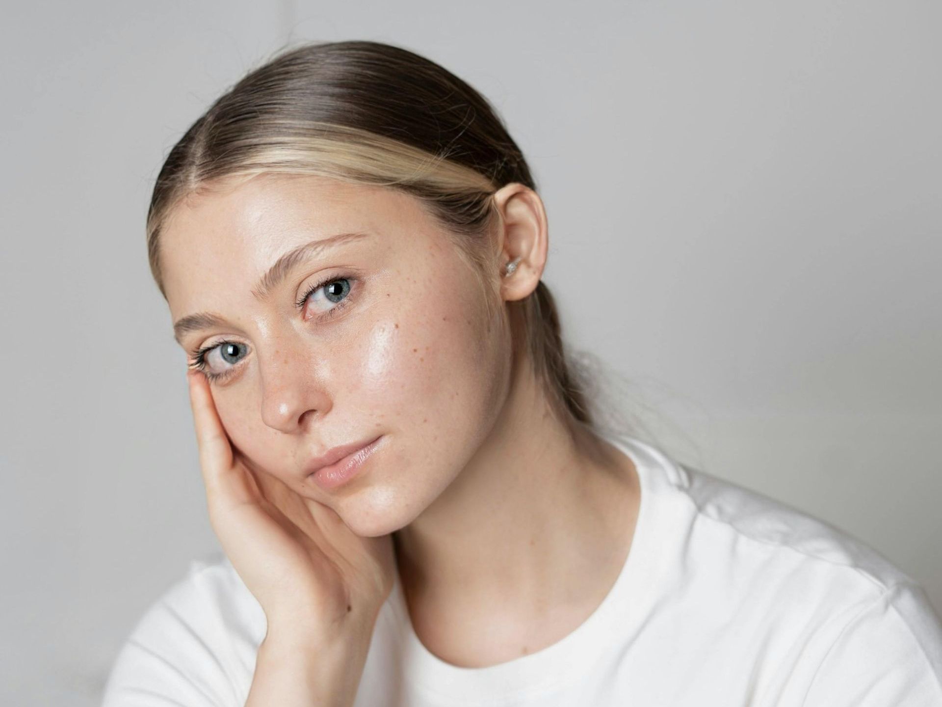 A close up of a woman 's face with her hand on her face.