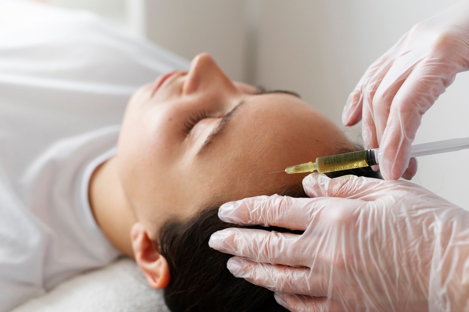 A woman is getting a botox injection in her forehead.