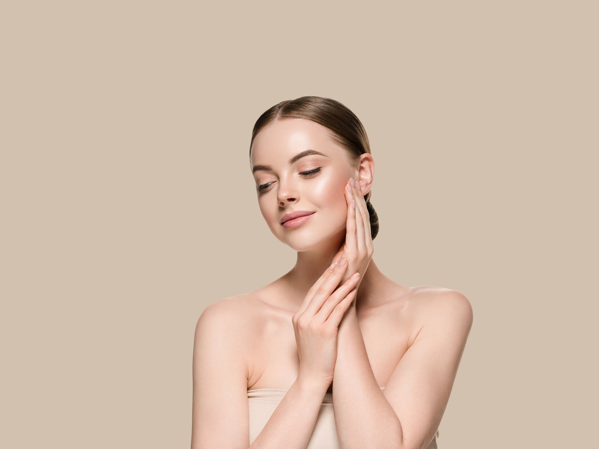 A woman is touching her face with her hands and smiling.