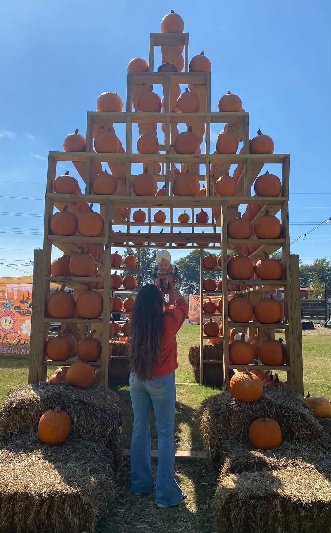 A woman is standing in front of a display of pumpkins.