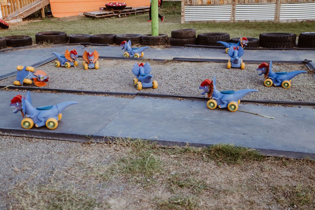 A row of toy dinosaurs sitting on top of a lush green field.