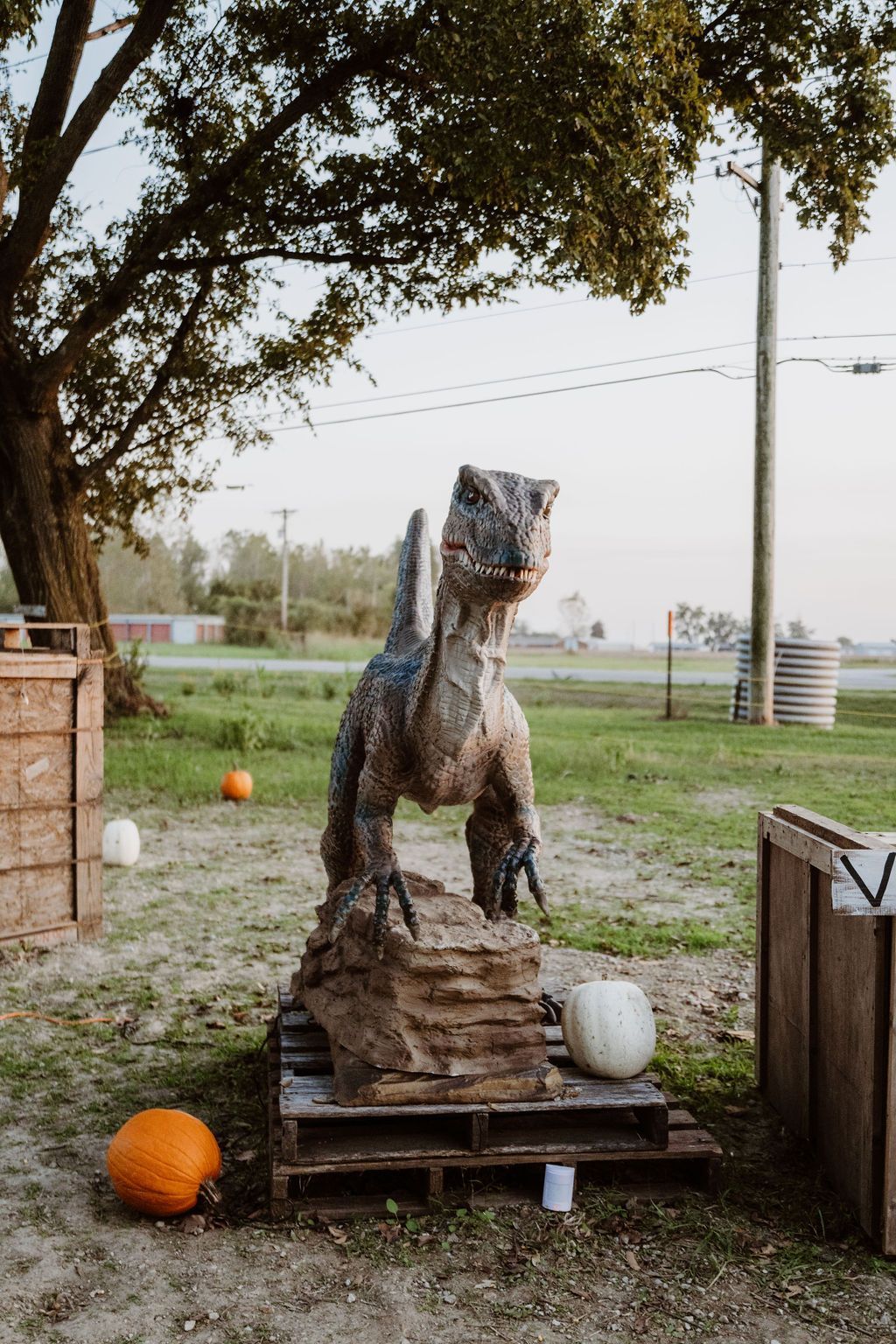 A group of children are standing around a dinosaur statue.