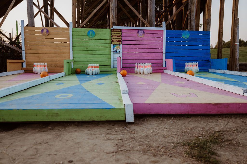 A little girl in a cheerleader outfit is standing in front of a roller coaster