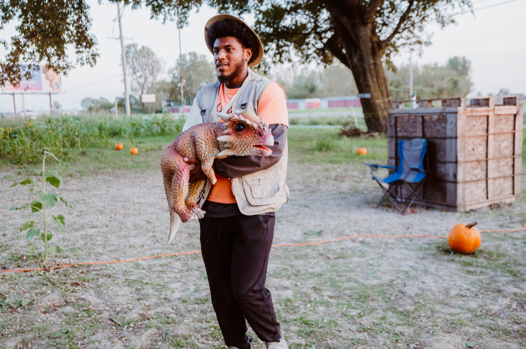A man is holding a pig in his arms in a field.