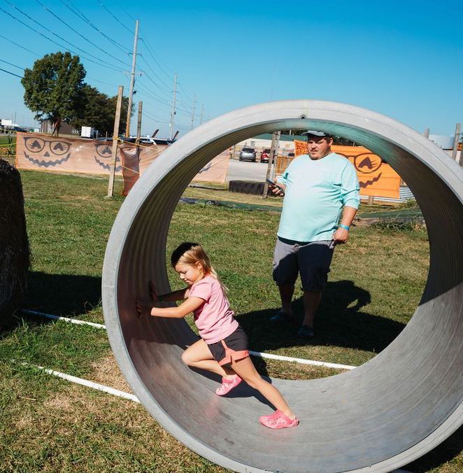 A boy and a girl are playing in a large concrete pipe.