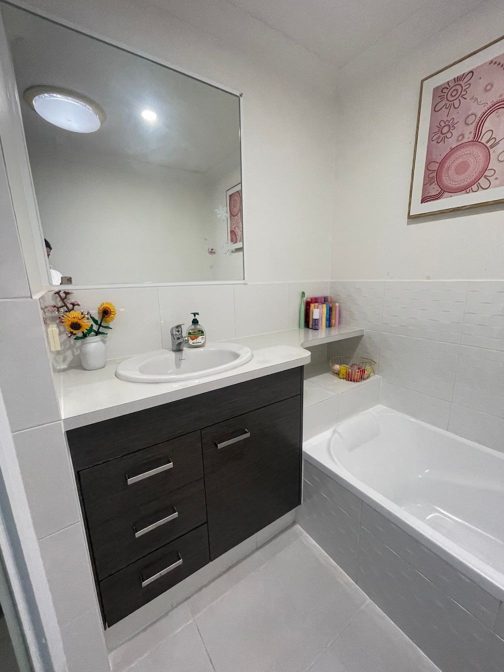 Bathroom with dark brown vanity, white countertop and tub.