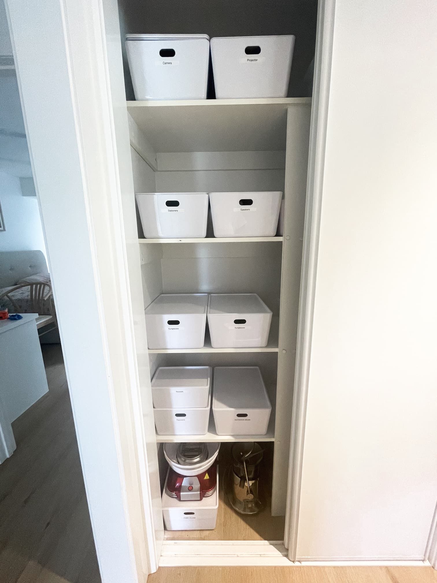A white closet with shelves, organized with white square bins of various sizes.