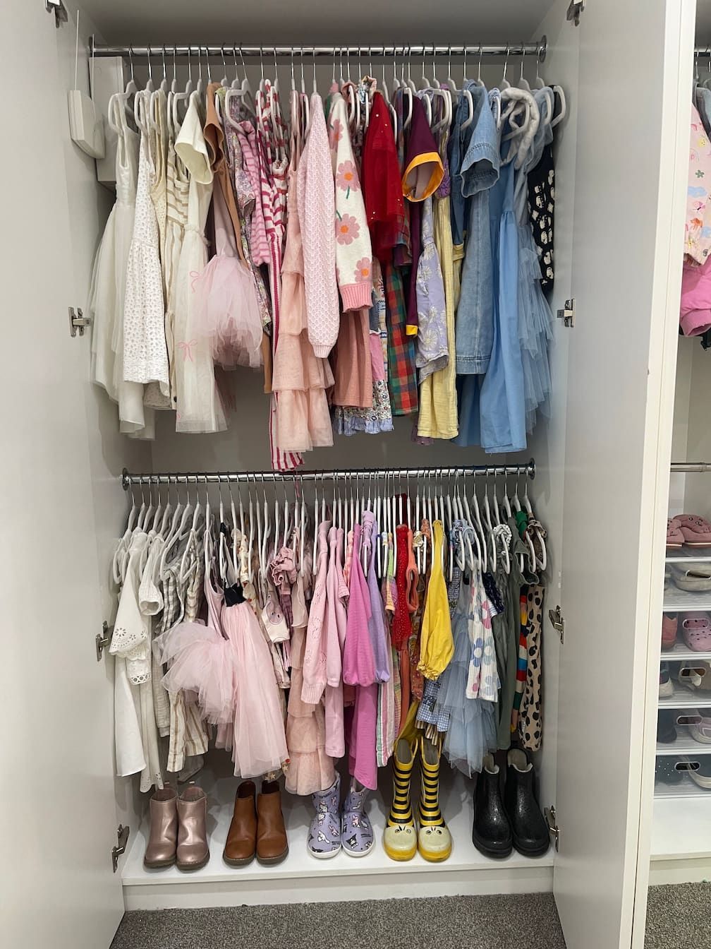 Closet filled with colorful children's clothes on hangers, plus boots.
