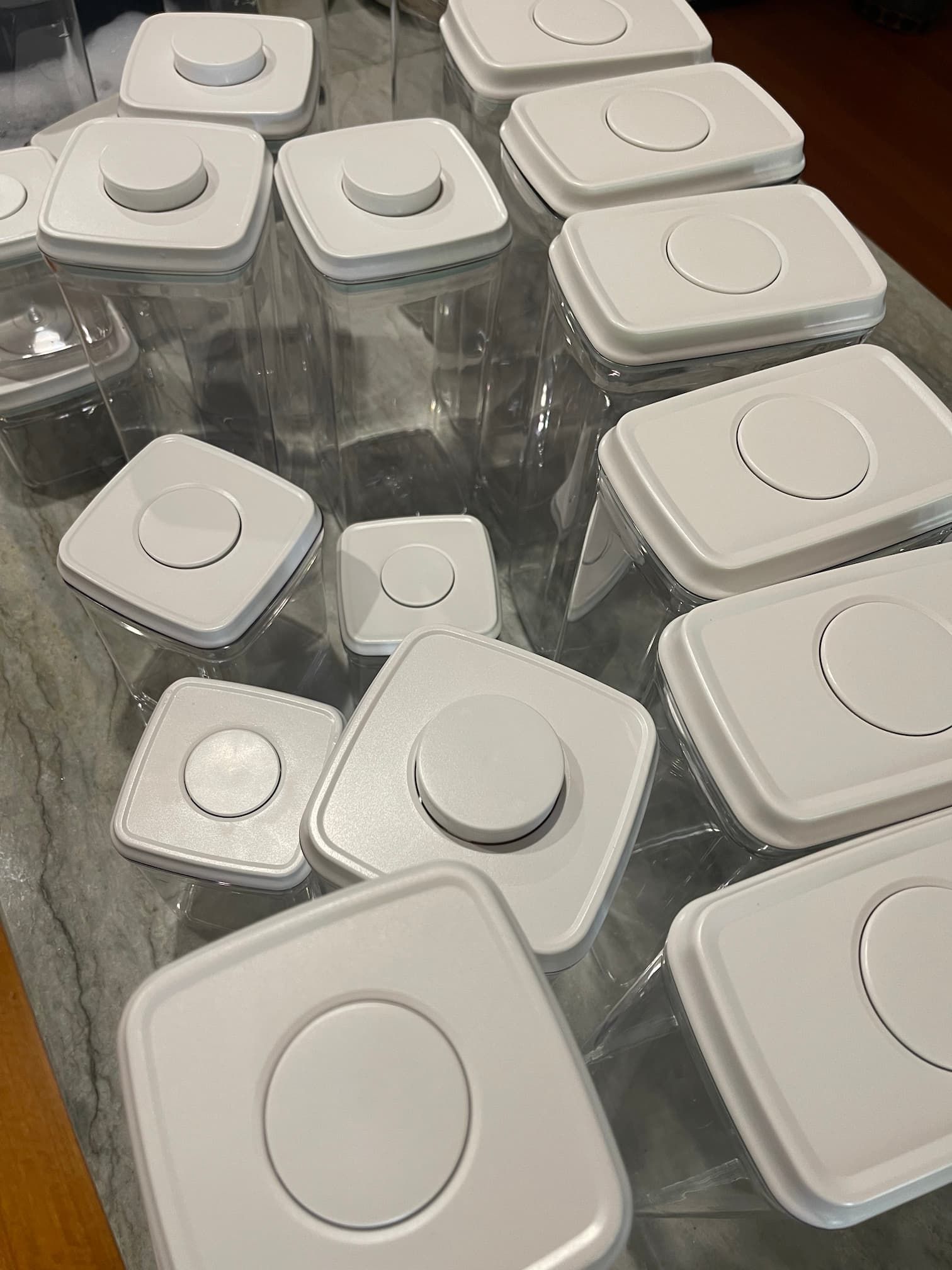White square lids with circular centers are stacked on a clear, plastic surface, likely storage containers.