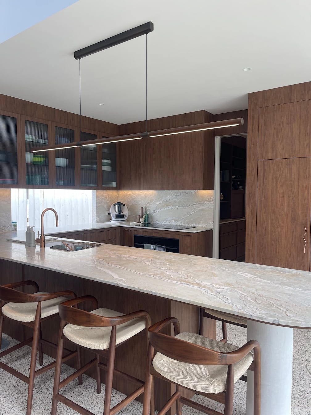 Modern kitchen with wood cabinets, island with stools, and pendant lighting.