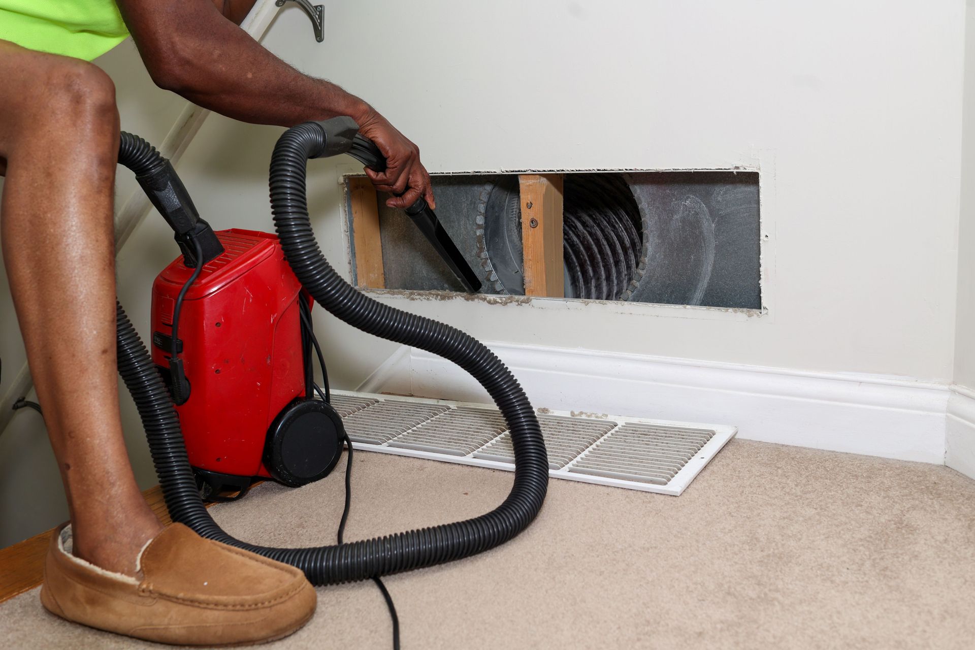 A portrait of a man cleaning an air duct.