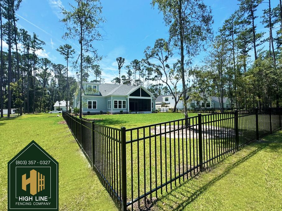 A wooden fence is surrounded by trees in a backyard.