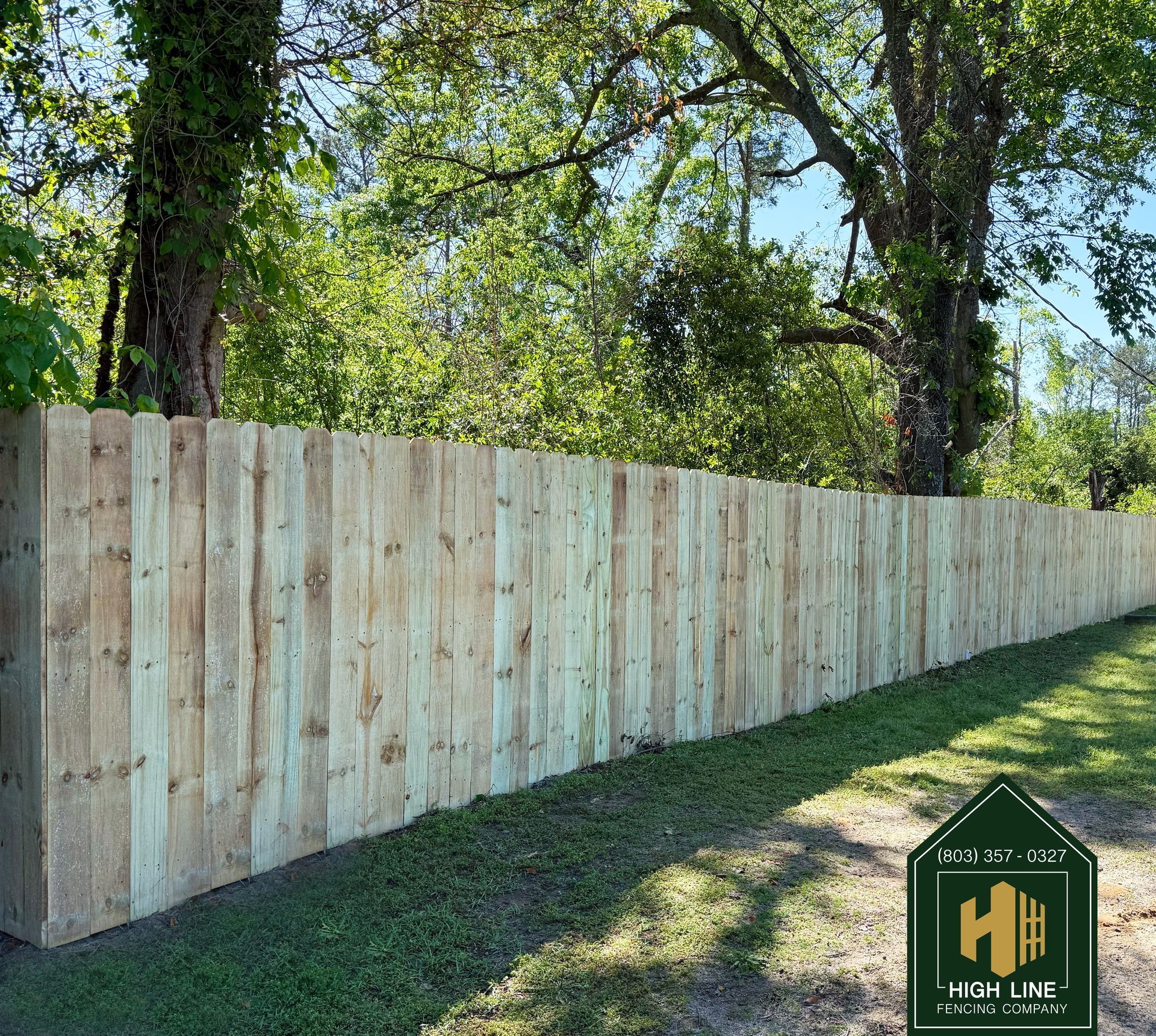 A black wooden fence surrounds a lush green lawn in front of a house.