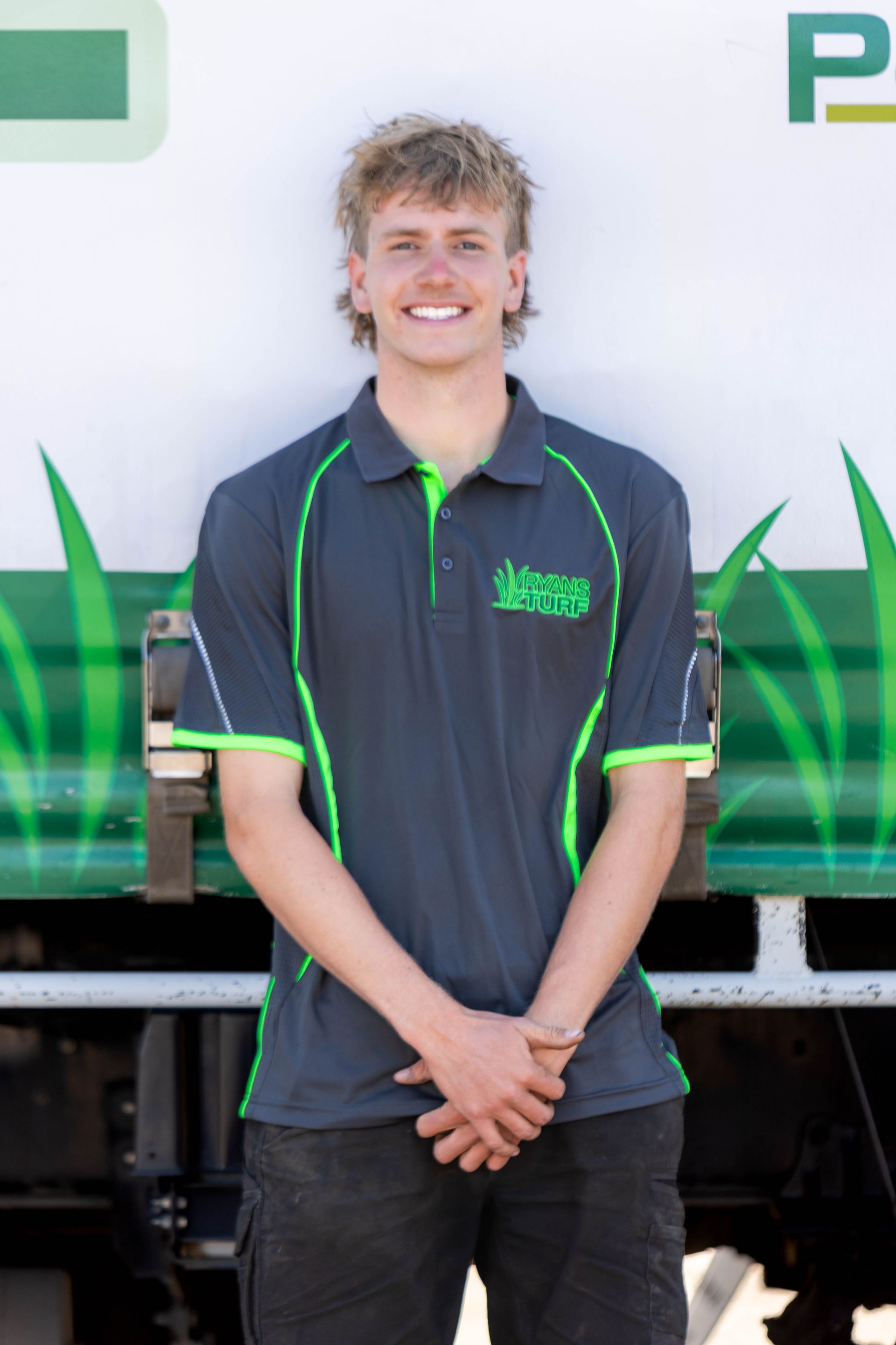 Red tractor mowing green grass in a field.
