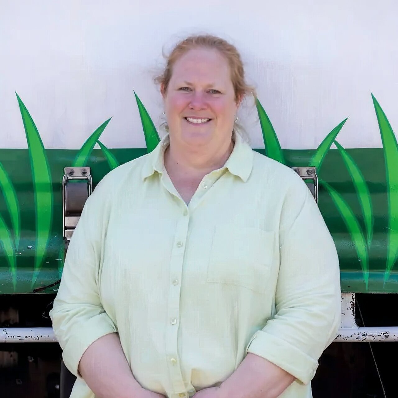 Red tractor mowing green grass in a field.