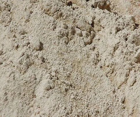 Close-up of a pile of light beige sand, with varying textures and slight shadows.