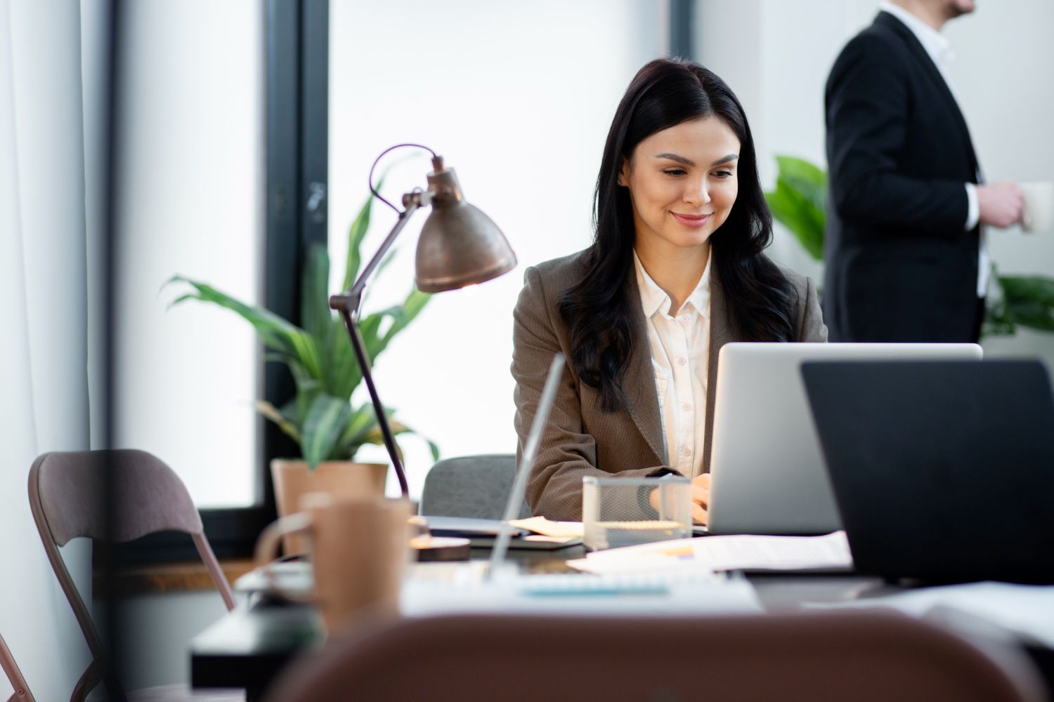 A woman is sitting at a desk in front of a laptop computer.