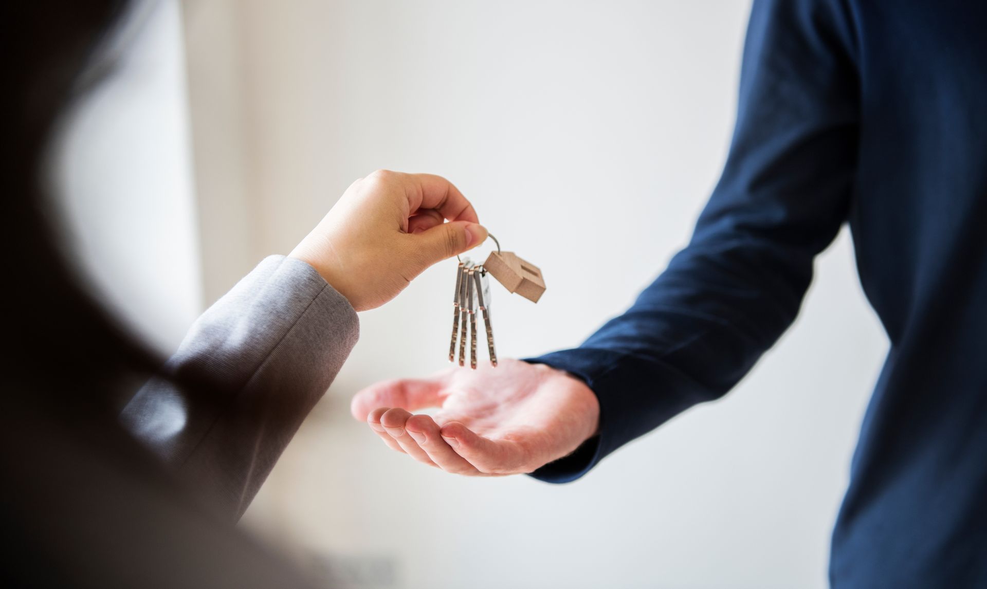 A person hands over a set of keys to another person in a business setting.