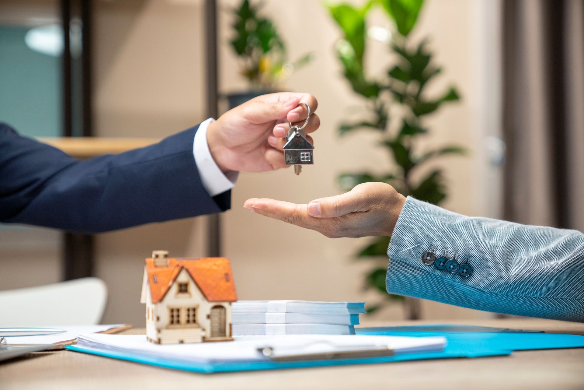 A man is handing a key to a woman in front of a model house.