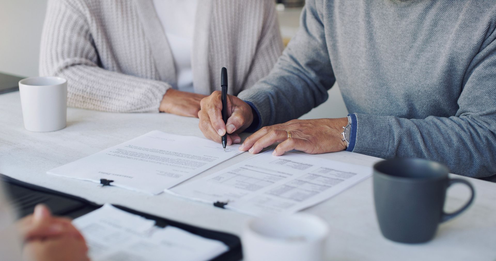 A man and a woman are sitting at a table signing a document.