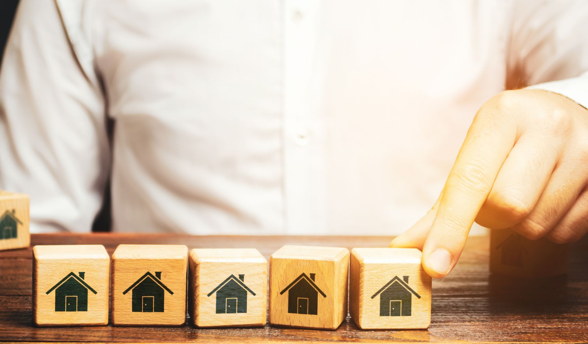 A person is holding a wooden block with a house on it.