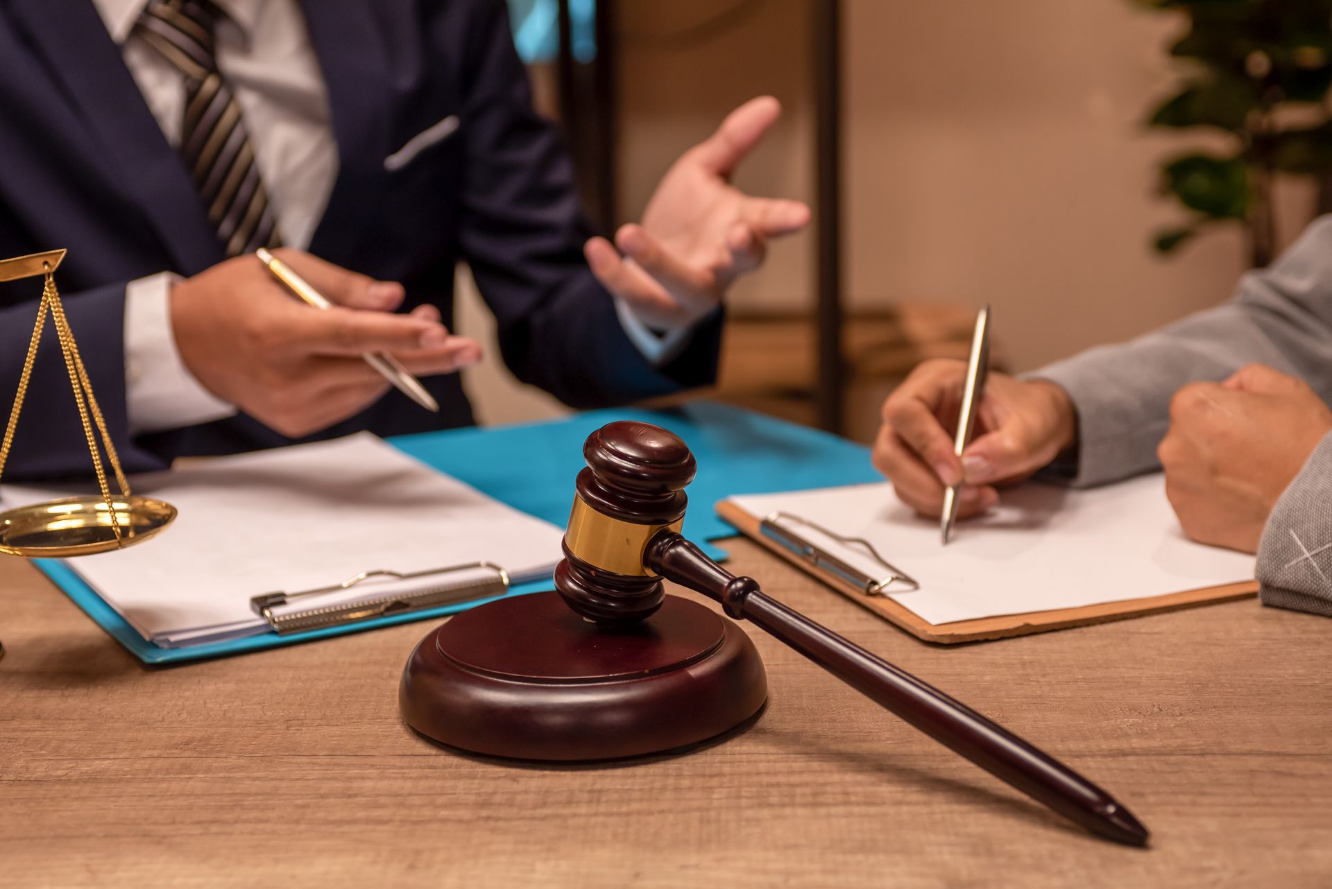 A judge 's gavel is sitting on a wooden table next to a clipboard.