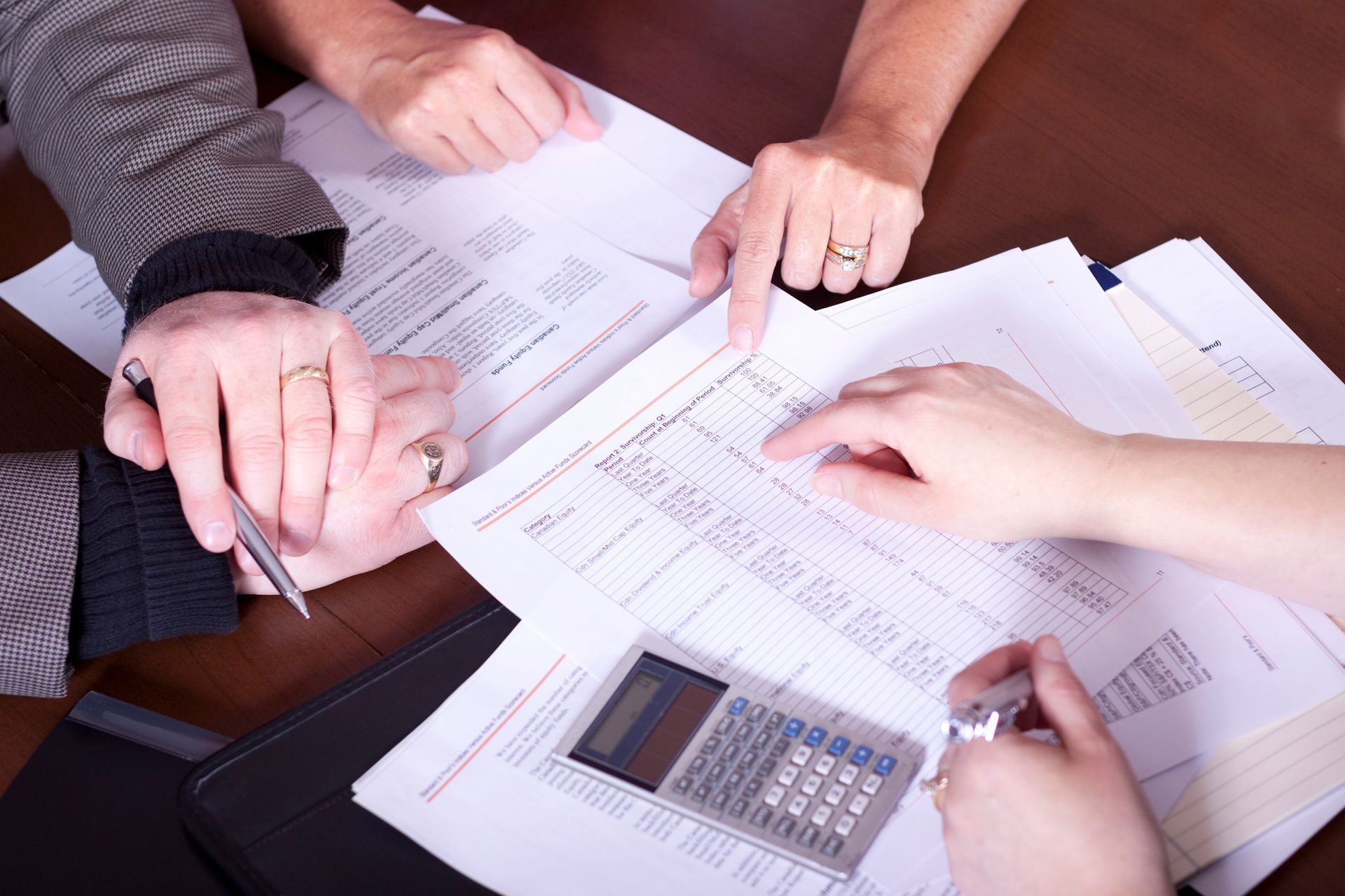 A group of people are sitting at a table with papers and a calculator.