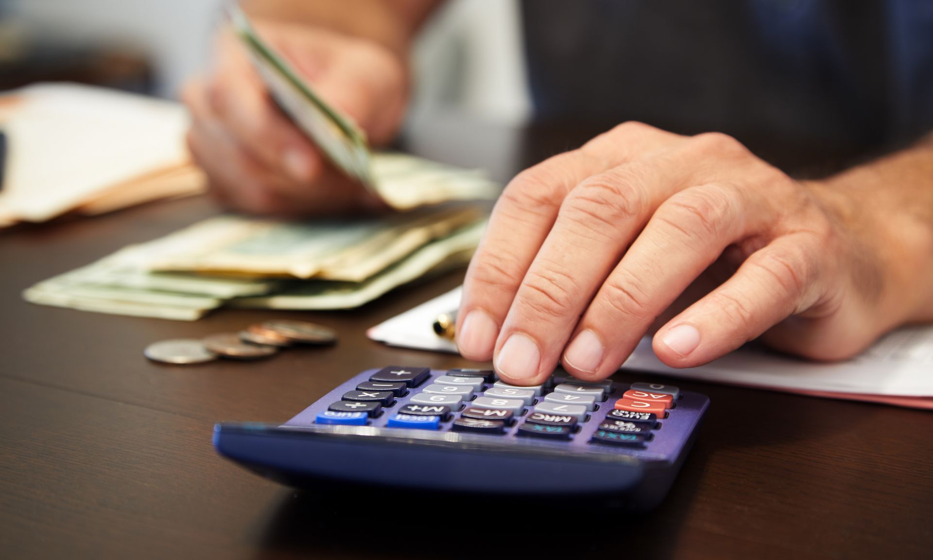 A person is using a calculator while holding a credit card.