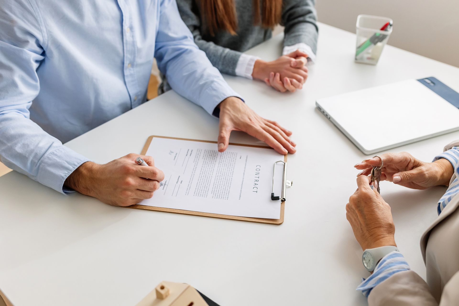 A man and a woman are sitting at a table signing a document.