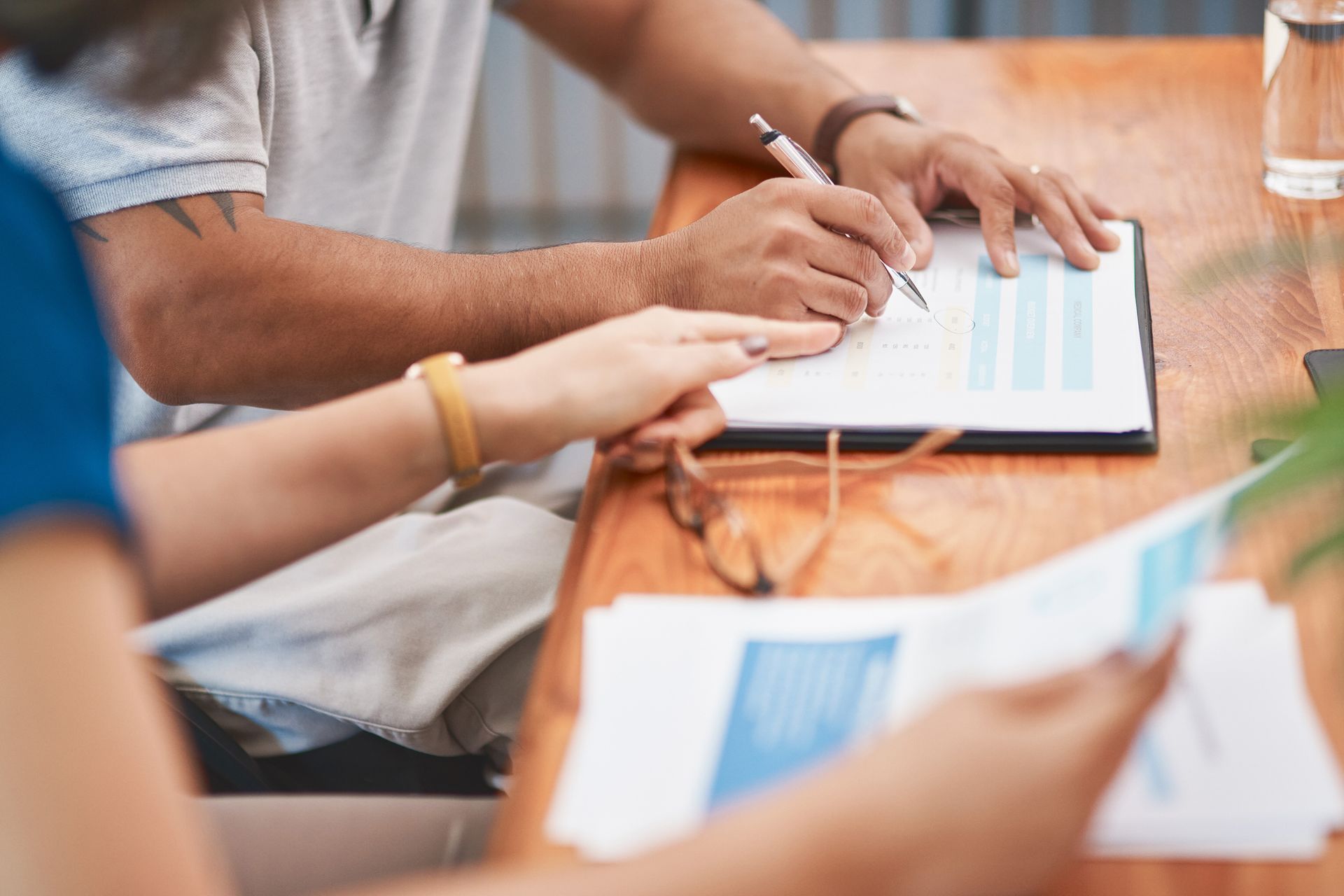 A man and a woman are sitting at a table looking at a clipboard.