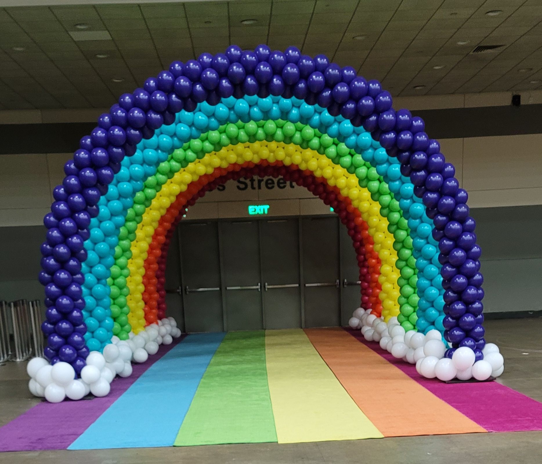 a rainbow made out of balloons in front of an exit sign