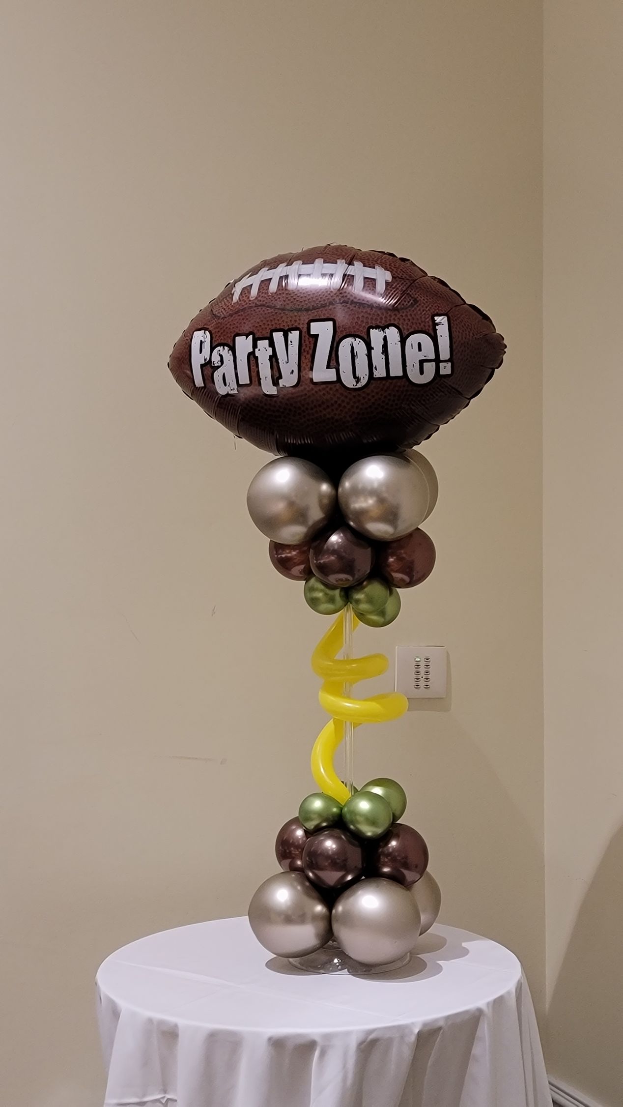 a football balloon is sitting on top of a table with balloons .