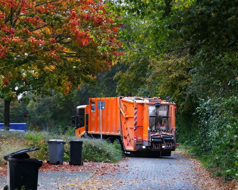orange garbage collection truck on a stone paved street orange garbage collection truck on a stone paved street