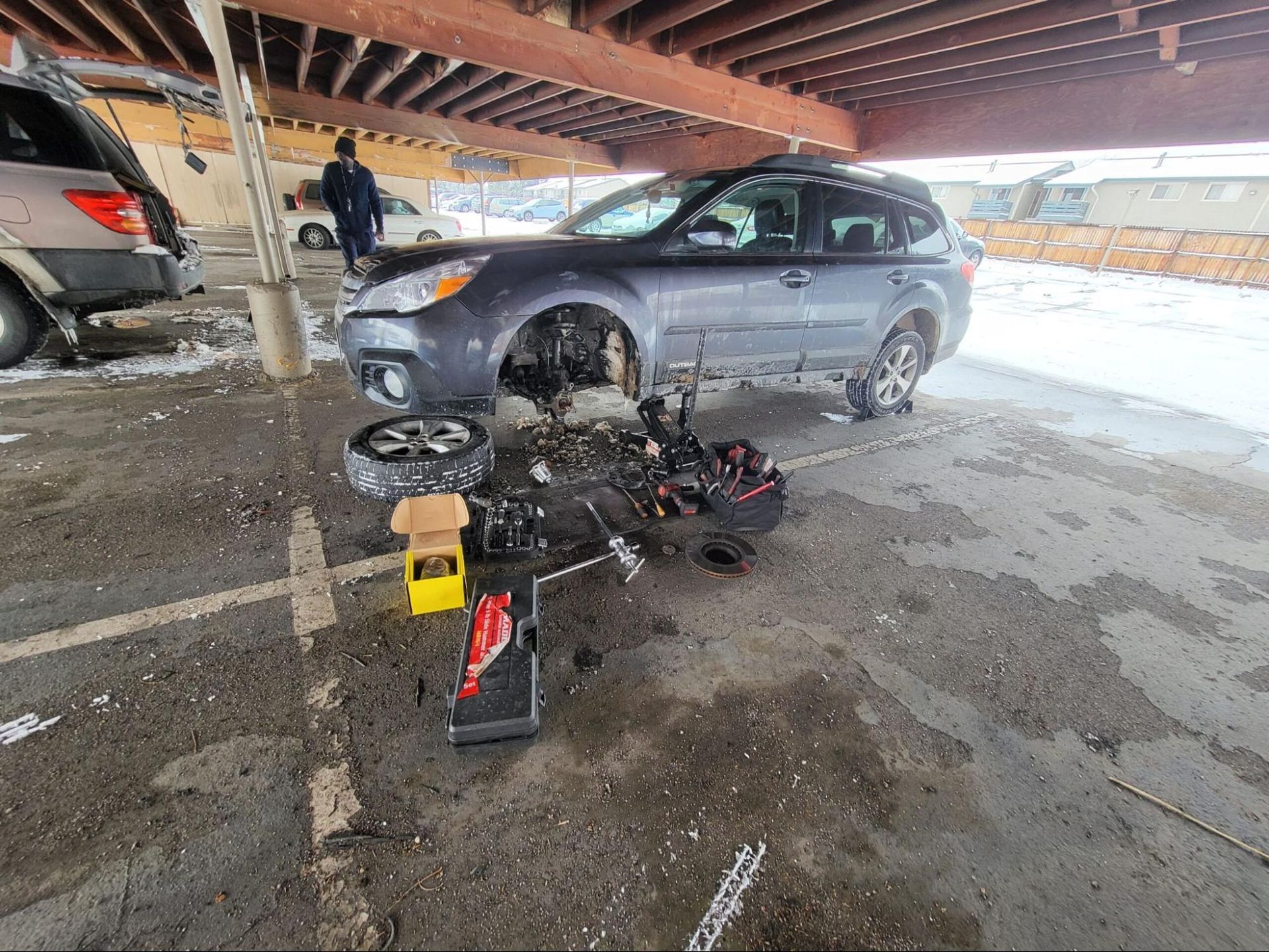 A car is being repaired in a parking lot.