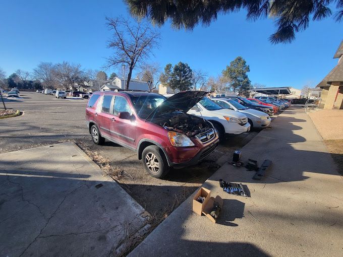 A red suv with its hood up is parked in a parking lot.