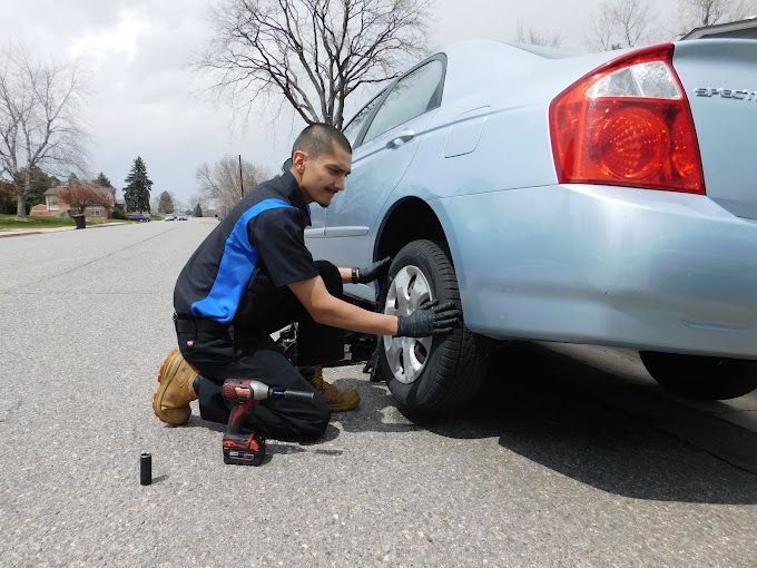 A man is changing a tire on a car with a drill.