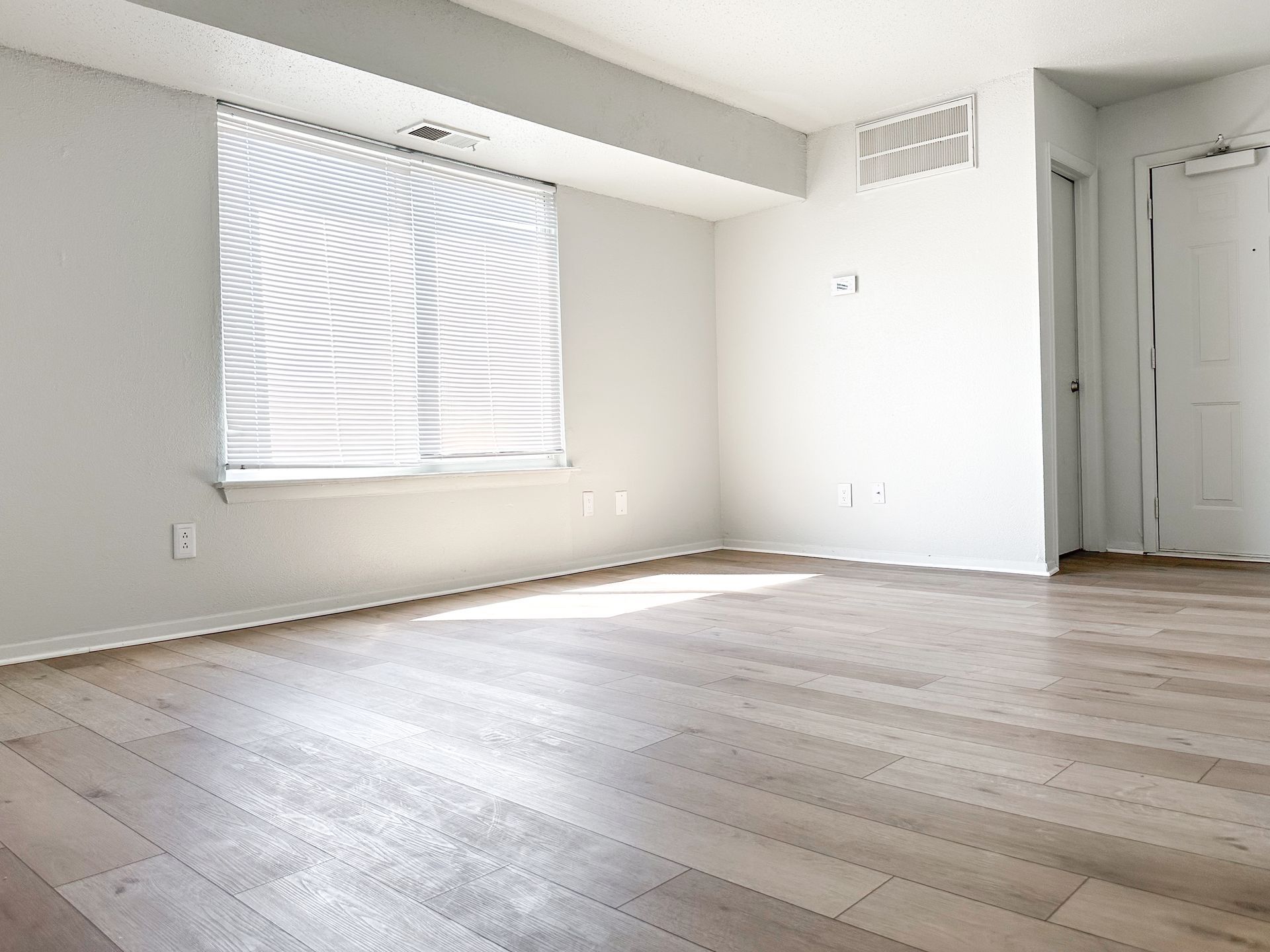 An empty living room with hardwood floors and a window.
